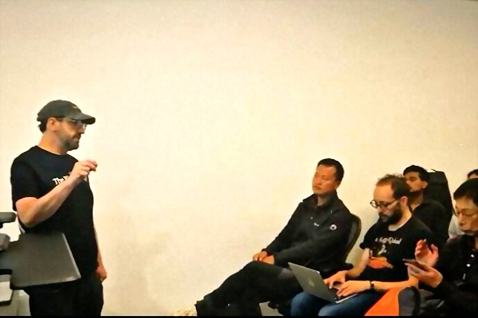 a speaker in a cap explaining his setup to the front row