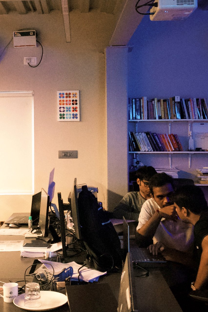 three builders working through a problem on one laptop